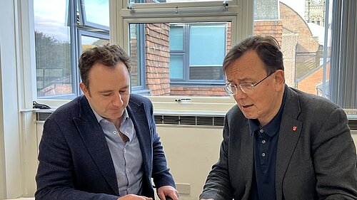 Danny Chambers MP and Martin Tod sitting in an office discussing a document